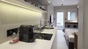 A modern kitchen with a built-in stove, a coffee machine, and a glass container on the counter. - Temple Apartments (Belgrade)
