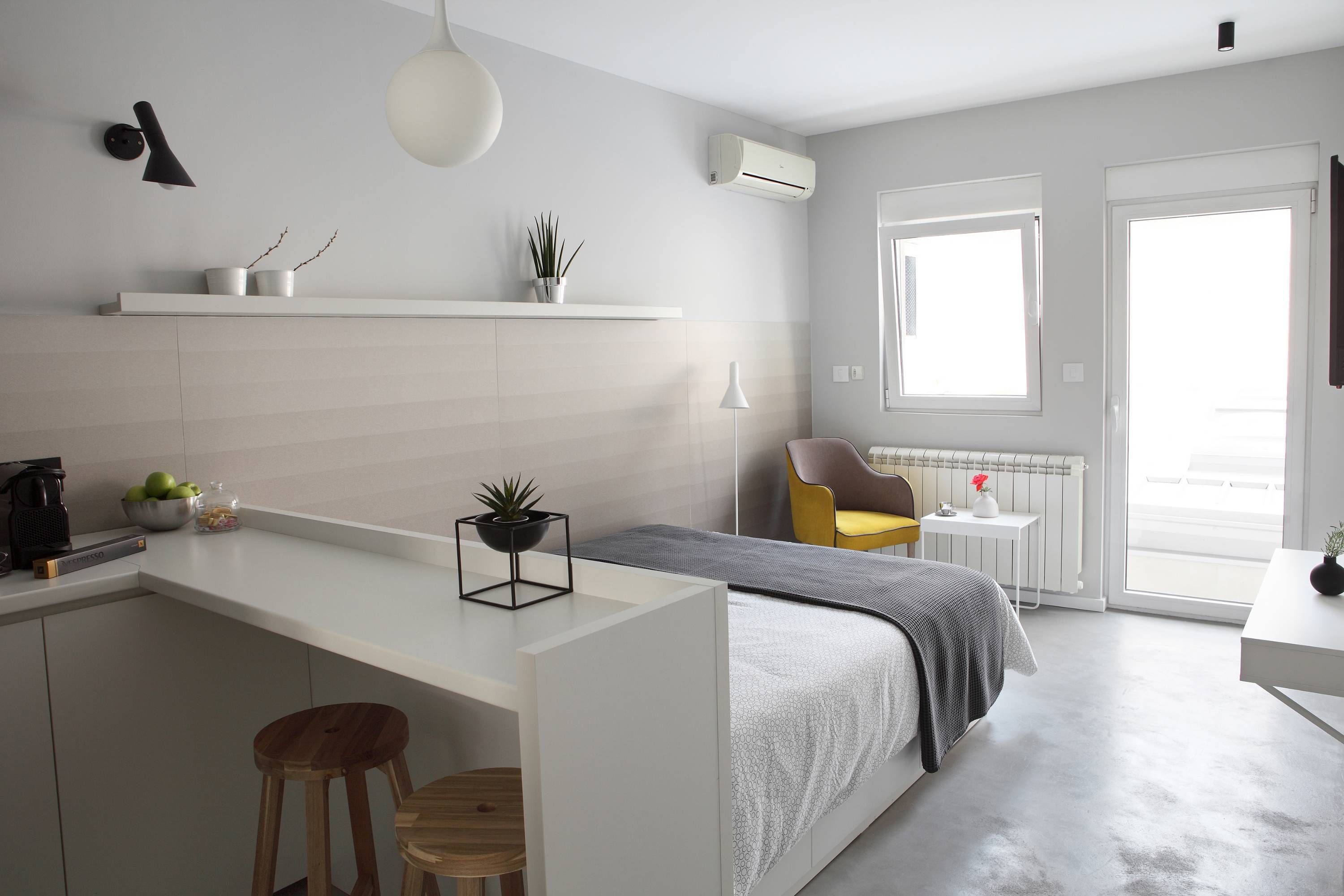 A modern, compact living space with a kitchenette, a bed, and a seating area.