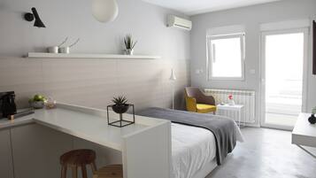 A modern, compact living space with a kitchenette, a bed, and a seating area.