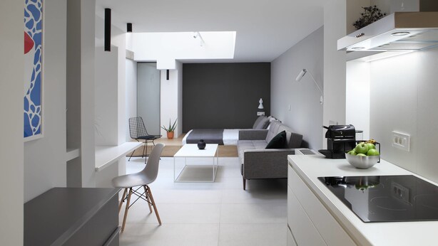 A modern kitchen with a central island, a dining area with a white table and chairs, and a living space with a sofa and a coffee machine. - Temple Apartments (Belgrade)