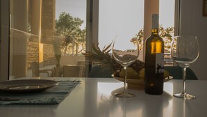 A table with a bottle of wine, two wine glasses, and a bowl of fruit. - Kalamaki Riviera Deluxe Apartment (Καλαμάκι)