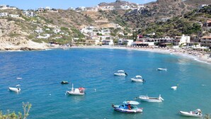 Un pueblo costero con barcos en el agua, edificios en las colinas y una playa.