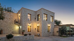 Un edificio de piedra con varias ventanas, un balcón e iluminación exterior.