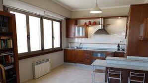 A kitchen with wooden cabinets, a white countertop, a built-in stove, and a window with blinds. - Barrañan Beach Apartments, Apartment 12 (Arteixo)