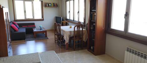 A spacious living area with a dining table, chairs, a sofa, and a bookshelf.