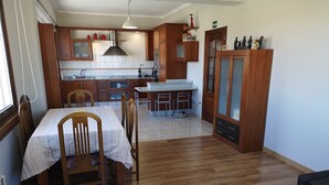 A compact kitchen with wooden cabinets, a dining table with chairs, and a small island with a sink. - Barrañan Beach Apartments, Apartment 12 (Arteixo)
