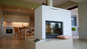 Eine moderne Küche mit weißen Schränken, ein Essbereich mit Holzsesseln und ein großes Fenster.