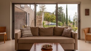 Ein Wohnzimmer mit einem beigefarbenen Sofa, einem Holztisch und einer Schiebetür zu einem Garten.