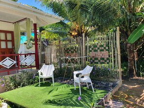 A garden area with two white plastic chairs, a small table, and a bamboo fence.