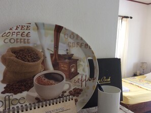 A coffee-themed wall decoration with a coffee cup and beans, a coffee grinder, and a notebook.