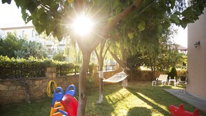 A backyard with a play area including a slide, a hammock, and a red swing set. - Villa in a great place of Rethymno, minutes away of the most famous beaches! (Κοξαρέ)