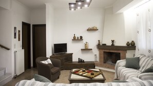 A living room with a fireplace, a television, and a chessboard on the floor. - Villa in a great place of Rethymno, minutes away of the most famous beaches! (Κοξαρέ)