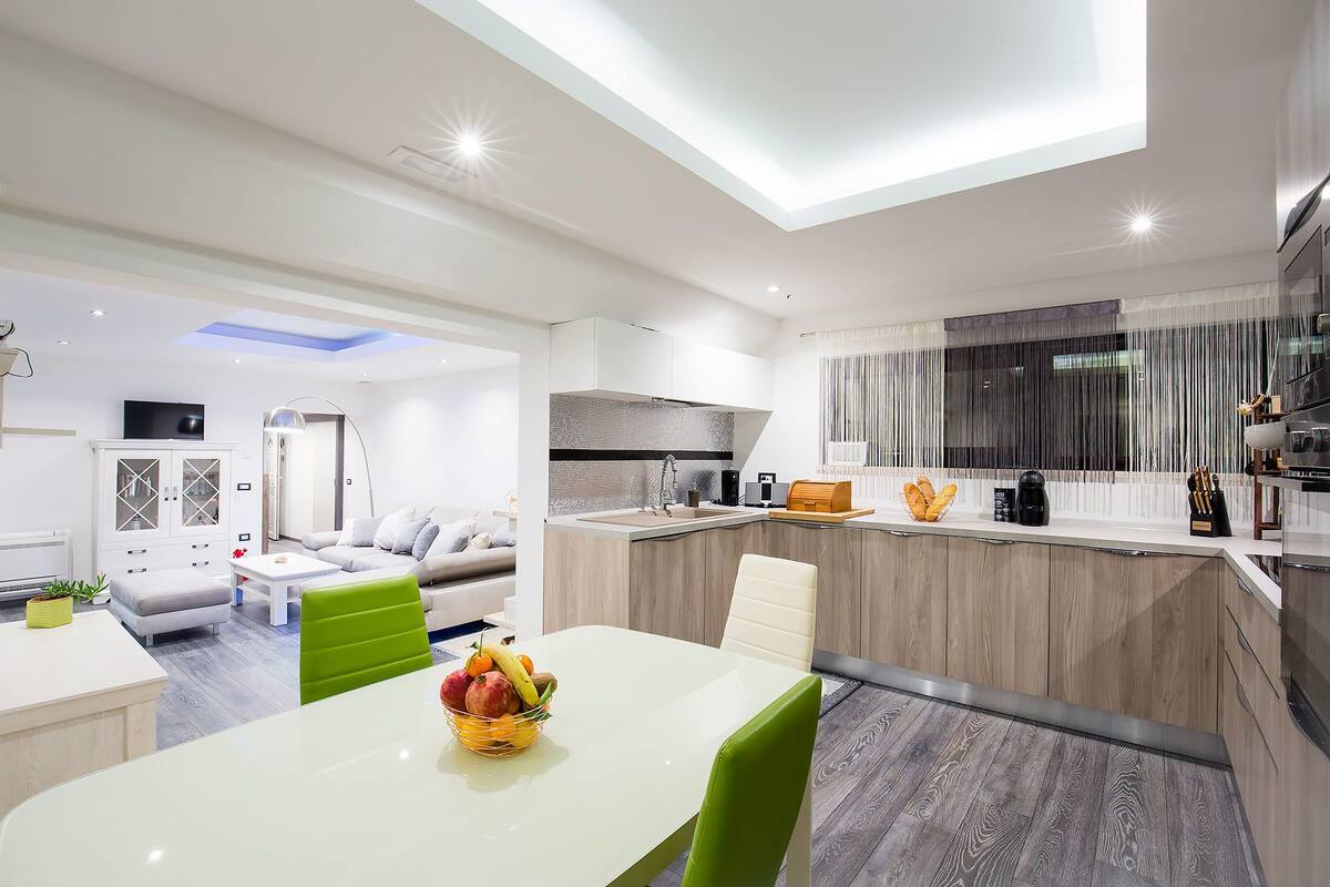A modern apartment with a dining area, kitchen, and living room.