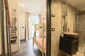 A hotel room with a bunk bed, a bathroom with a shower, and a view of the outdoors. - Apartments Delfin Villa Sofia (Umag)