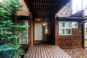 A wooden house with a front porch, a door, and windows. - River Glen Condos by CRMR (Frisco)