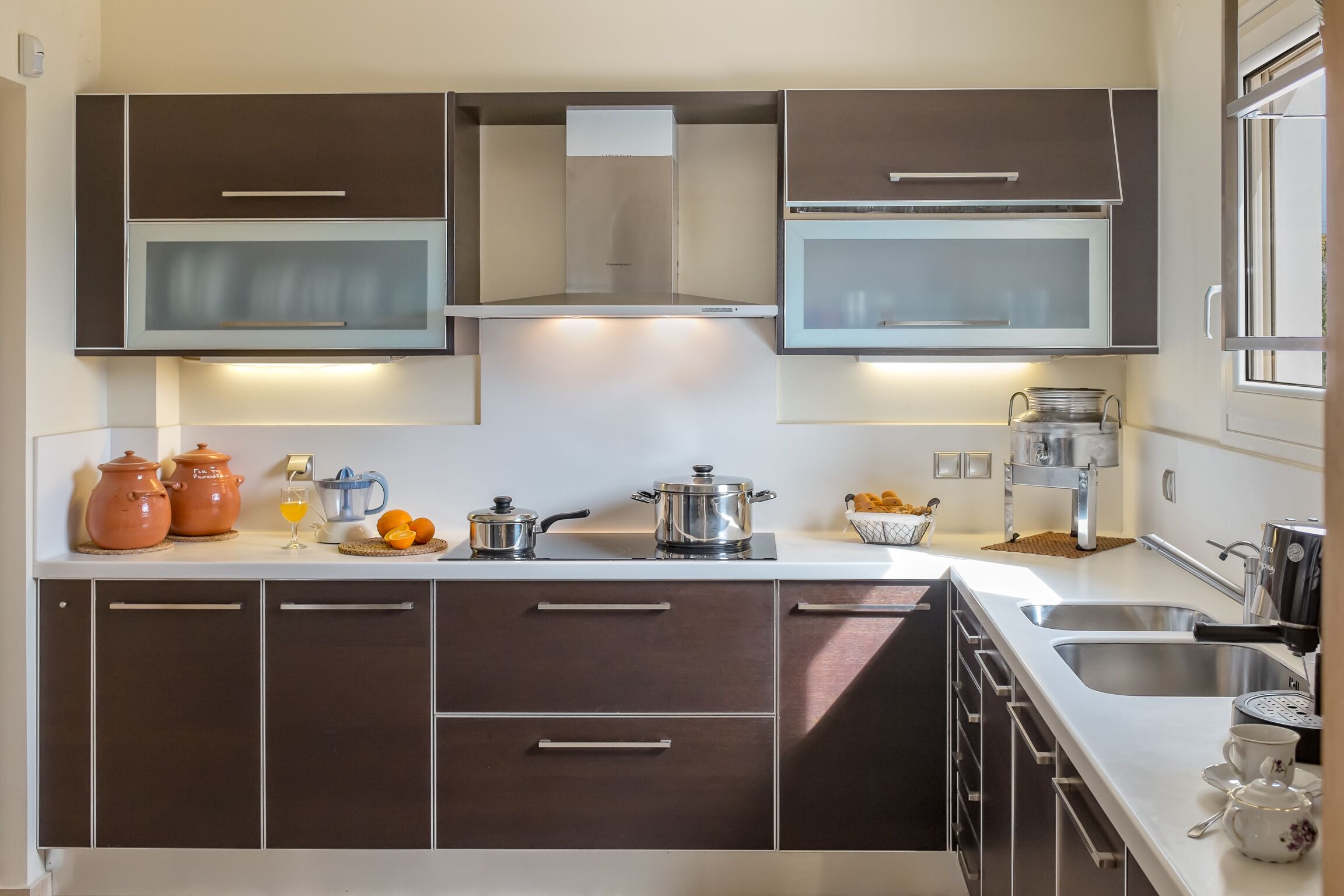 A modern kitchen with dark cabinets, stainless steel appliances, and a white countertop.
