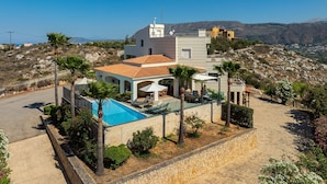 A modern villa with a swimming pool, outdoor seating, and a view of the surrounding hills. - Karmilos Hill Villa - close to the center of Chania with private swimming pool. (Χανιά)
