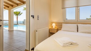 A bedroom with a bed, bedside lamp, and a view of a swimming pool. - Karmilos Hill Villa - close to the center of Chania with private swimming pool. (Χανιά)