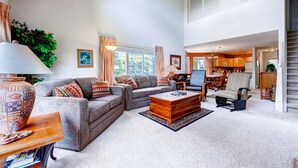 A spacious living room with a grey sofa set, a wooden coffee table, and a large vase on a side table. - Bay Club Town Homes by CRMR (Frisco)
