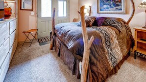 Un dormitorio con una cama grande, cabecera de madera, una mesita de noche y una puerta con espejo.