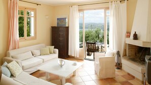 A spacious living room with a white sofa, a coffee table, and a view through a glass door to the outdoors. - Villa Pergola - Collection Villas (Katouna)