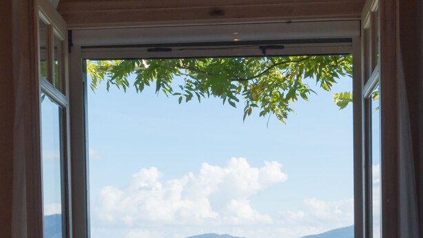 A balcony with a view of a lake and mountains, a table with a fruit bowl, and two chairs. - Villa Pergola - Collection Villas (Katouna)