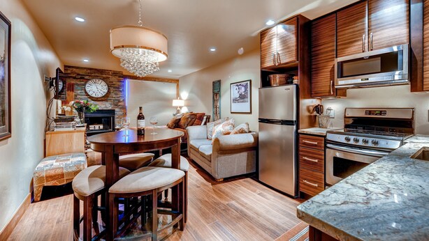 A modern kitchen with wooden cabinets, stainless steel appliances, and a marble countertop. - Cedars Lodge Condos by CRMR (Frisco)