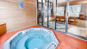 A hot tub with a wooden deck and glass doors leading to a dining area. - Cedars Lodge Condos by CRMR (Frisco)