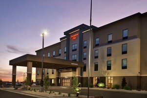 A Hampton Inn hotel with a modern design, featuring a covered entrance and multiple windows.