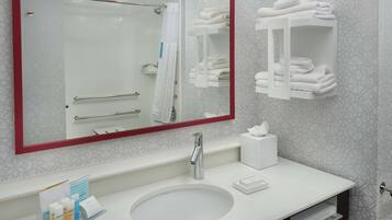 Un baño moderno con un espejo grande, un lavabo blanco y un perchero para toallas.