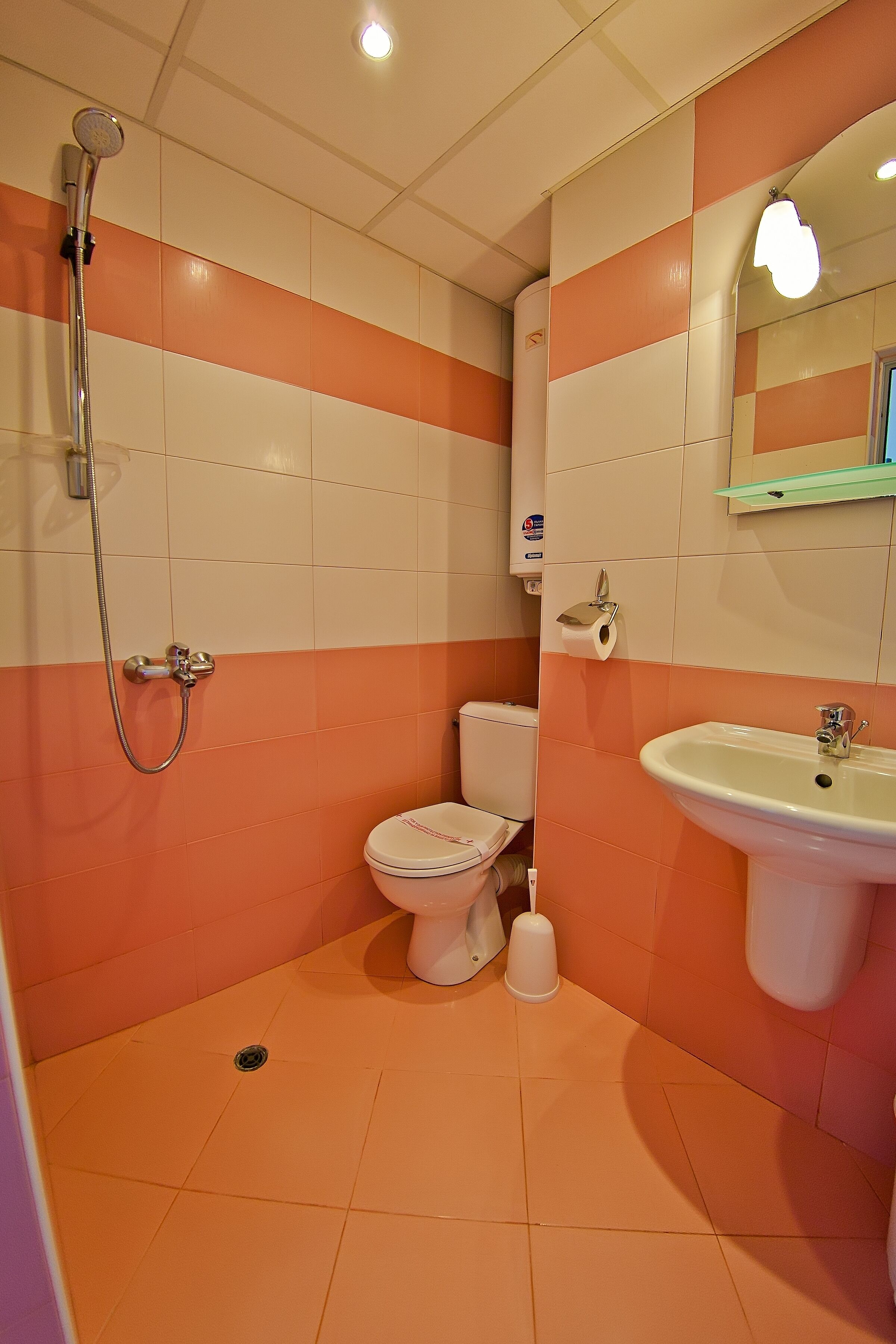 A bathroom with a shower, toilet, sink, and a mirror.