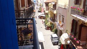 A narrow street with buildings on both sides, balconies with flower pots, and a parked vehicle. - Entire Family Friendly House "Villa Archondisa" in the Old Town (Χανιά)