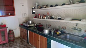 Una cocina con estufa a gas, un lavamanos y diversos utensilios y recipientes de cocina sobre la encimera.