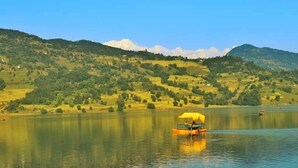 Un barco con toldo amarillo en un lago tranquilo rodeado de colinas verdes.