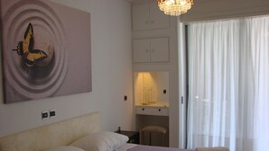 A hotel room with a bed, a desk, a chair, and a large window with curtains. - Luxury apart. w/ spectacular views (Loutraki-Korinthias)