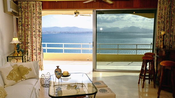 A living room with a sofa, a coffee table, and a view of the sea through a balcony. - Luxury apart. w/ spectacular views (Loutraki-Korinthias)