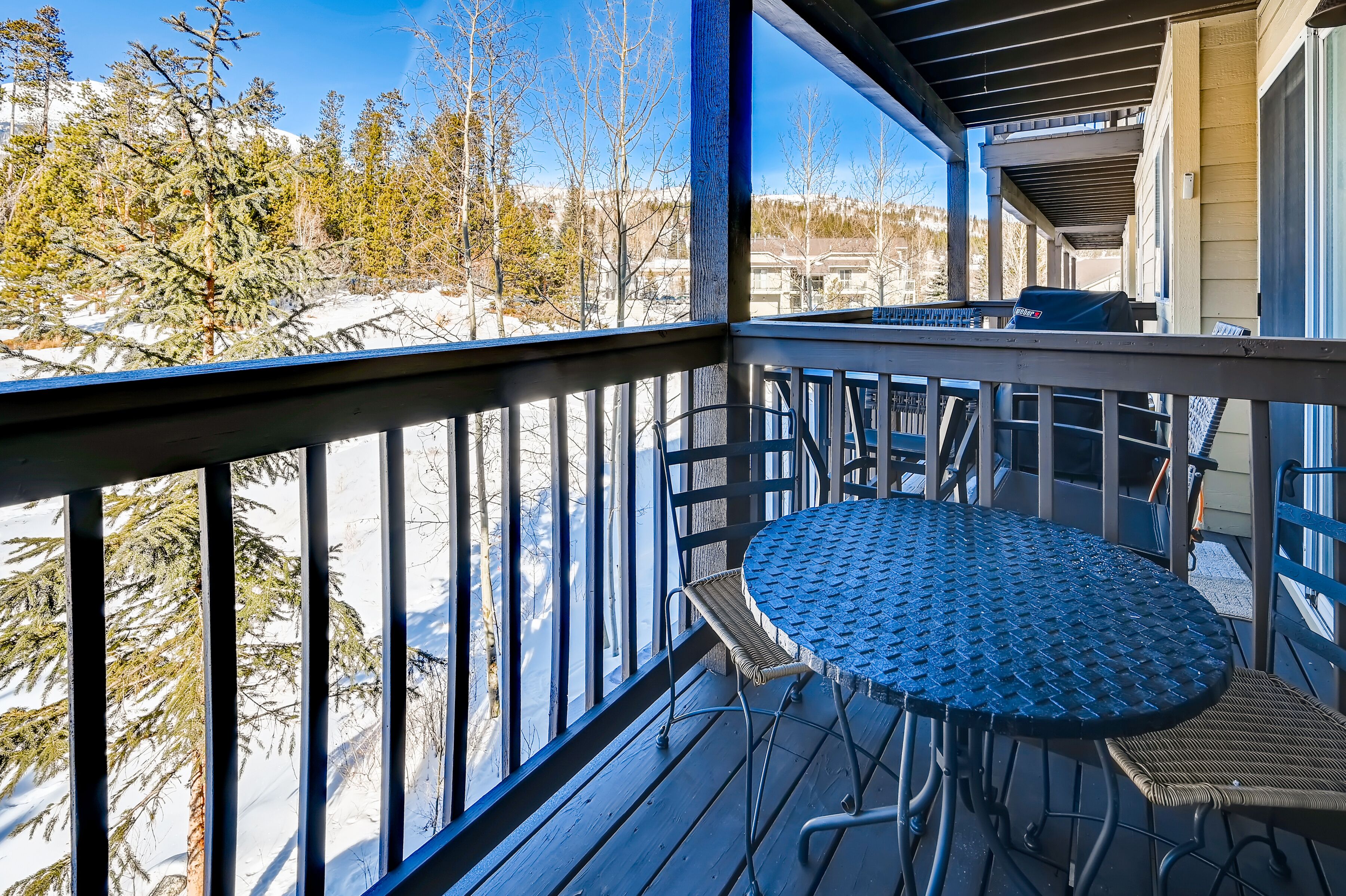 A covered outdoor area with a metal railing, a round table, and chairs.