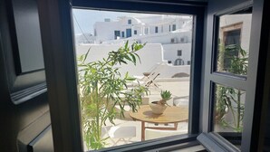 Une fenêtre donnant sur un bâtiment aux murs blancs et aux fenêtres bleues.