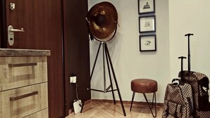 A room with a wooden cabinet, a tripod lamp, a framed picture on the wall, and a patterned bag. - Atenéo, a modern flat downtown Athens! AMA 00000054917 (Αθήνα)