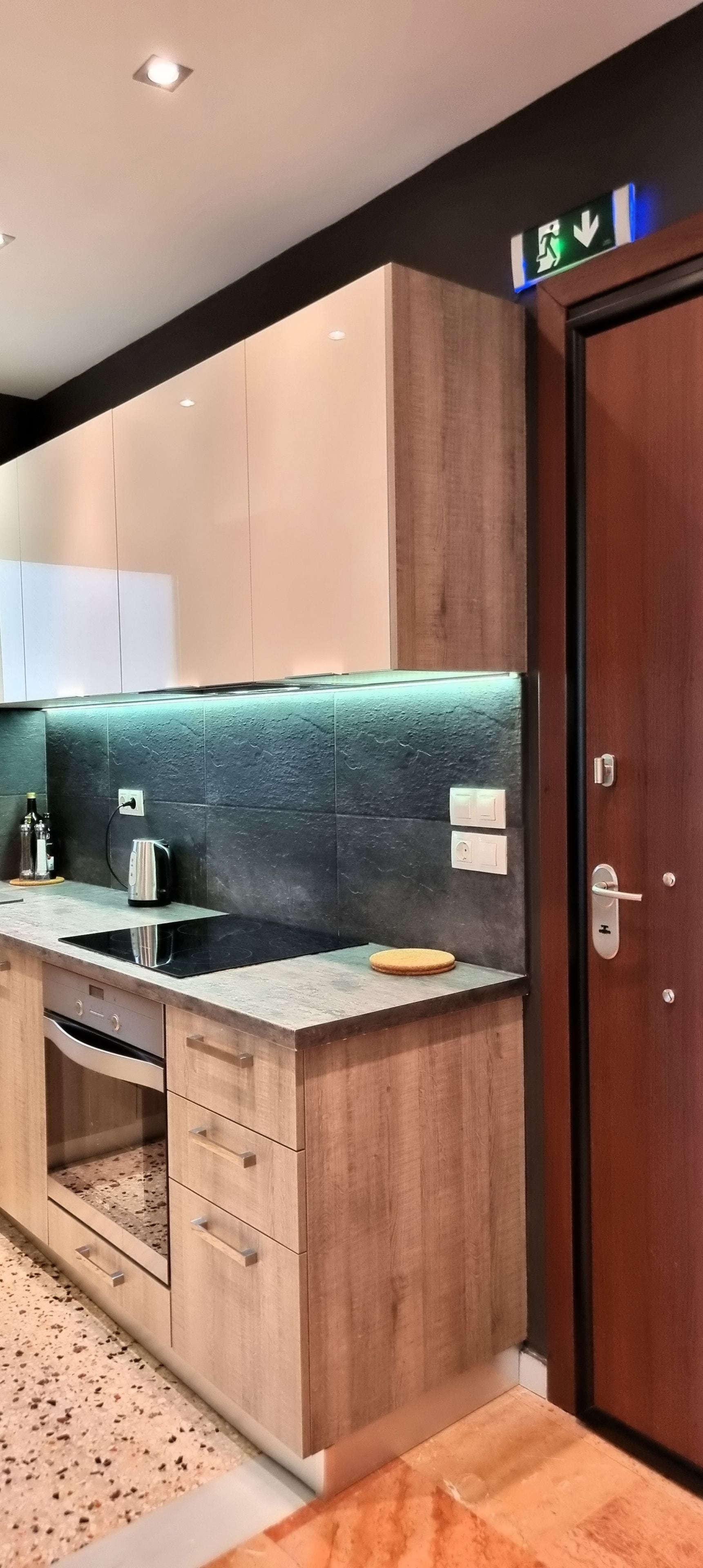 A modern kitchen with wooden cabinets, a countertop, and a built-in oven.