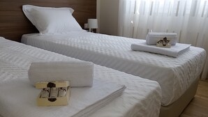 Hotellihuoneessa on kaksi sänkyä, joissa on valkoiset lakanat ja tyynyt. Sängyillä on siististi taiteltuja pyyhkeitä ja hygieniatarvikkeita.