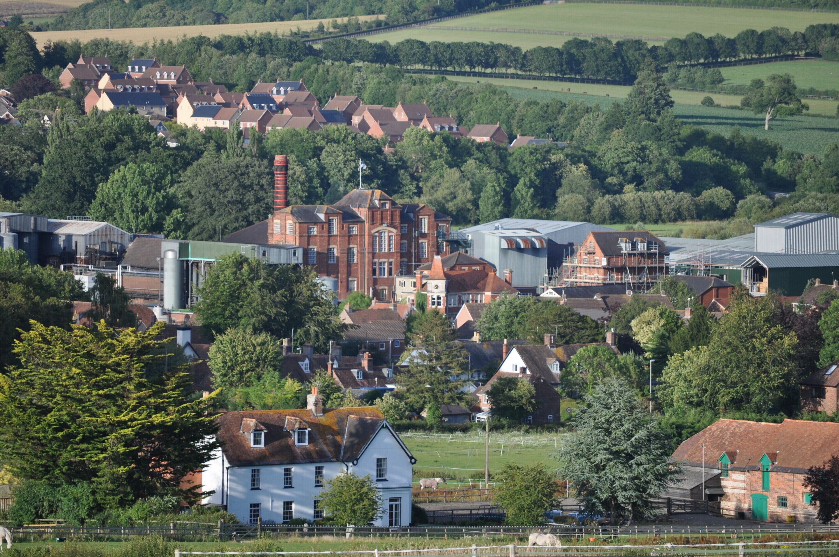 A rural town with a mix of residential and industrial buildings, surrounded by greenery.