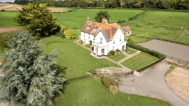 A large white house with a well-maintained lawn and a stone pathway leading to the entrance.