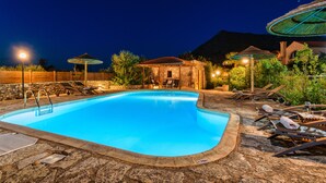 A swimming pool with lounge chairs and umbrellas, surrounded by stone walls and vegetation. - Luxury stone villa with outdoor jacuzzi, private pool and antique furniture (Πλάκα)