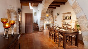 A rustic dining area with a stone fireplace, wooden beams, and a long wooden table with chairs. - Luxury stone villa with outdoor jacuzzi, private pool and antique furniture (Πλάκα)