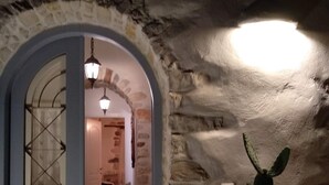 A stone-walled hallway with a wooden door and a potted plant. - Villa Petradi (200 meters from the sea)  4 kilometers from Naoussa. (Νάουσα)