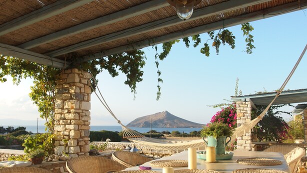 A terrace with wicker furniture, stone pillars, and a view of a mountain. - Villa Petradi (200 meters from the sea)  4 kilometers from Naoussa. (Νάουσα)