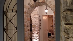 An arched stone corridor with a door leading to a room with a tiled floor and a hanging light fixture. - Villa Petradi (200 meters from the sea)  4 kilometers from Naoussa. (Νάουσα)