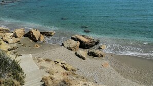 A coastal landscape with clear blue sea, rocky shore, and a concrete path leading to the beach. - Villa Petradi (200 meters from the sea)  4 kilometers from Naoussa. (Νάουσα)