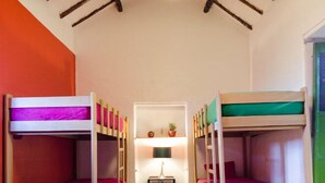 Una habitación con dos literas, una mesita con una lámpara y una luz en el techo.